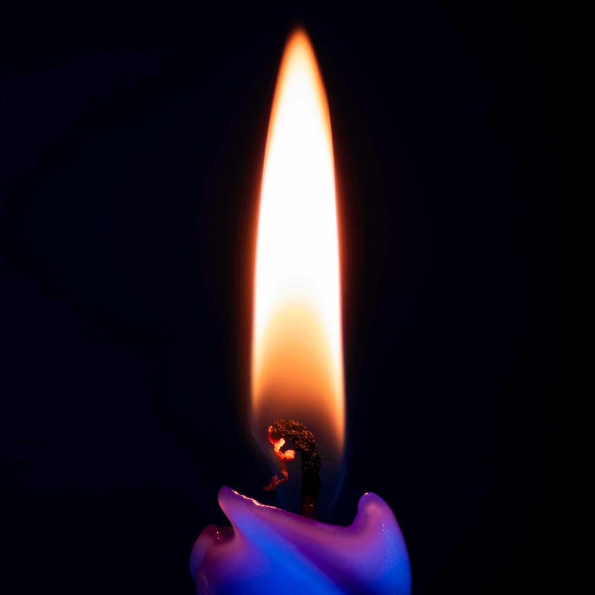 a candle with a blue flame on a black background