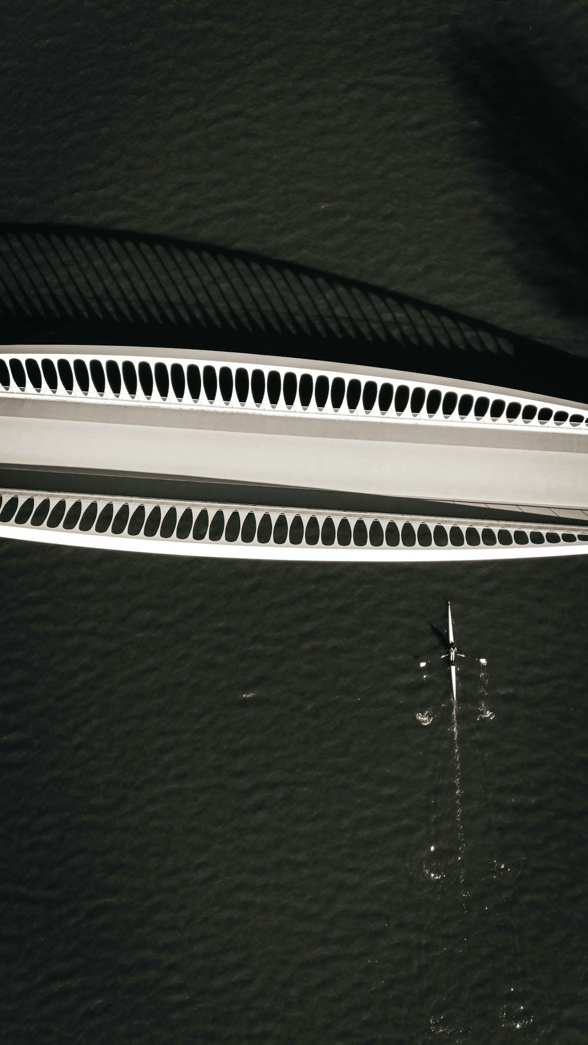 A bridge casts a shadow over a boat.