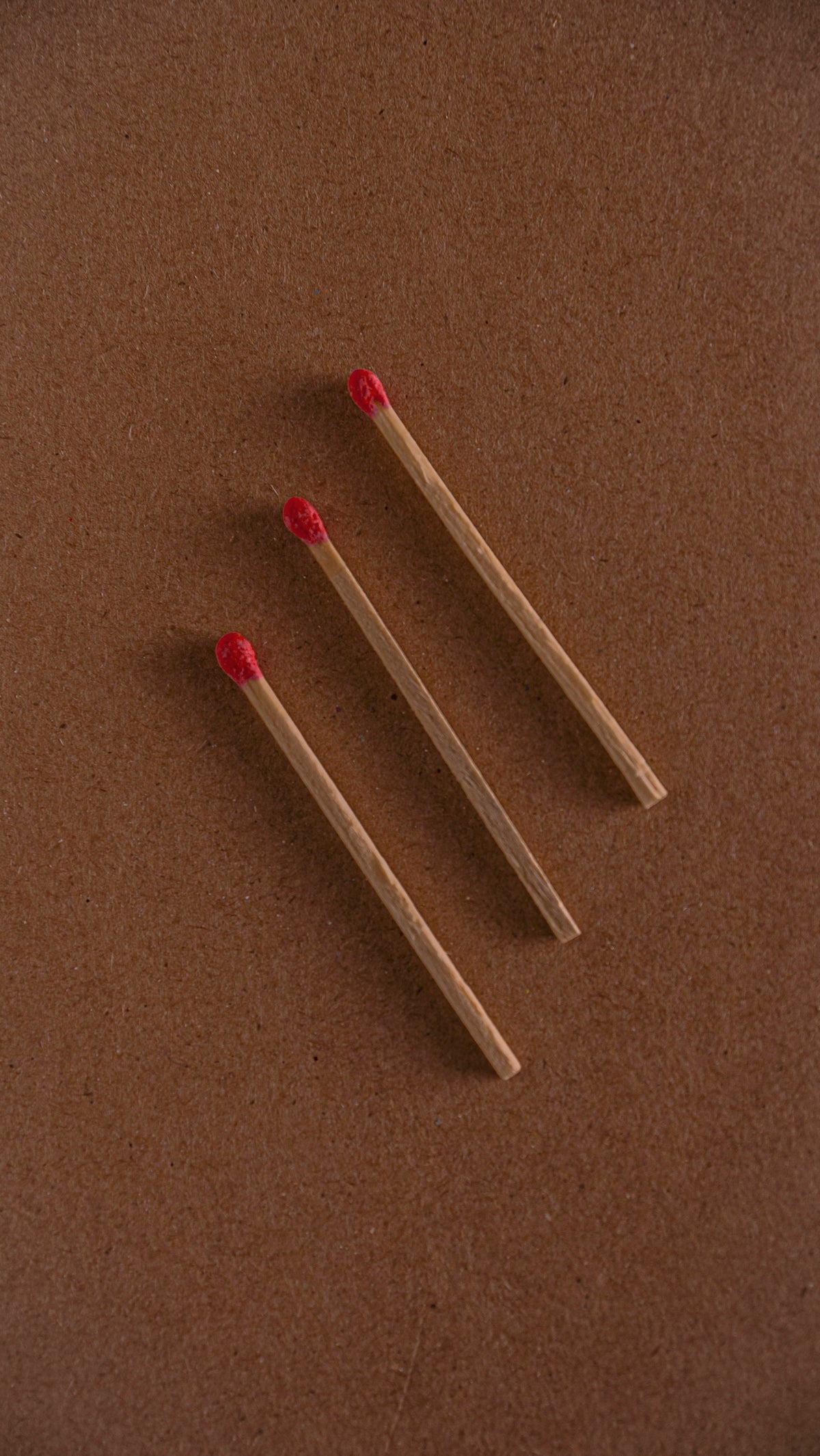 Three matches lie on a brown surface.