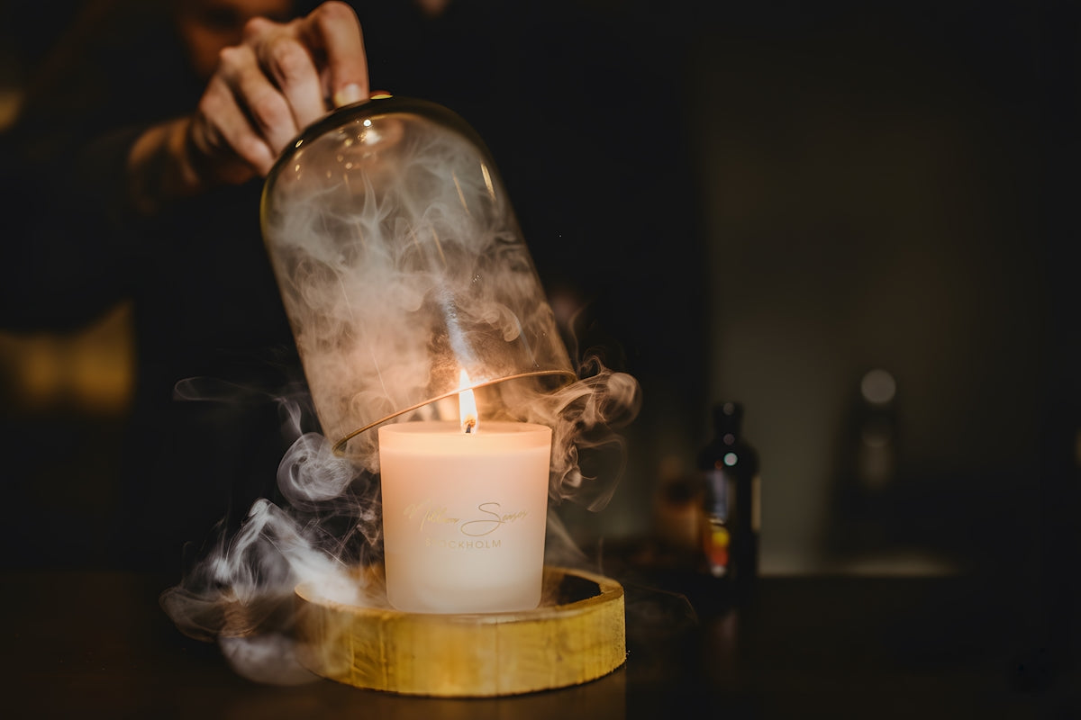 Candle smoke escapes from under a glass dome.
