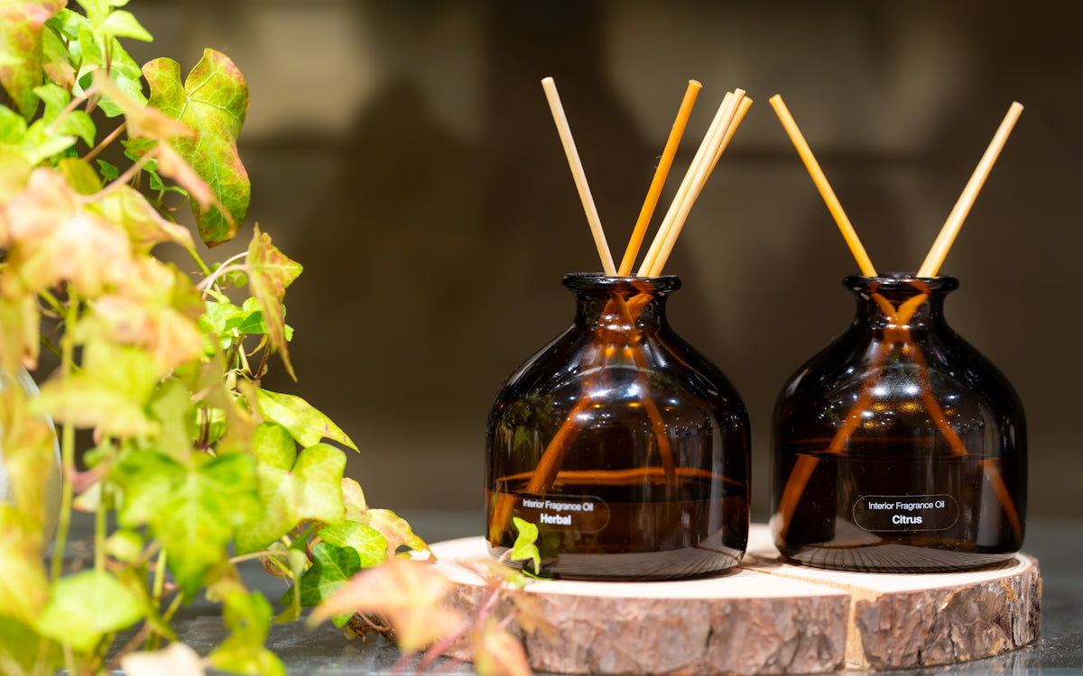 Two amber glass reed diffusers with wooden reeds.
