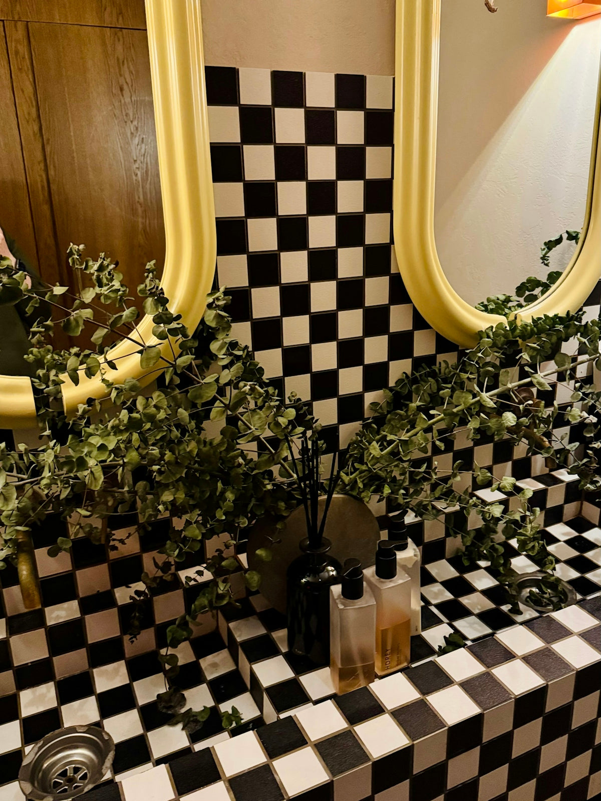 Bathroom vanity with checkerboard tiles and greenery