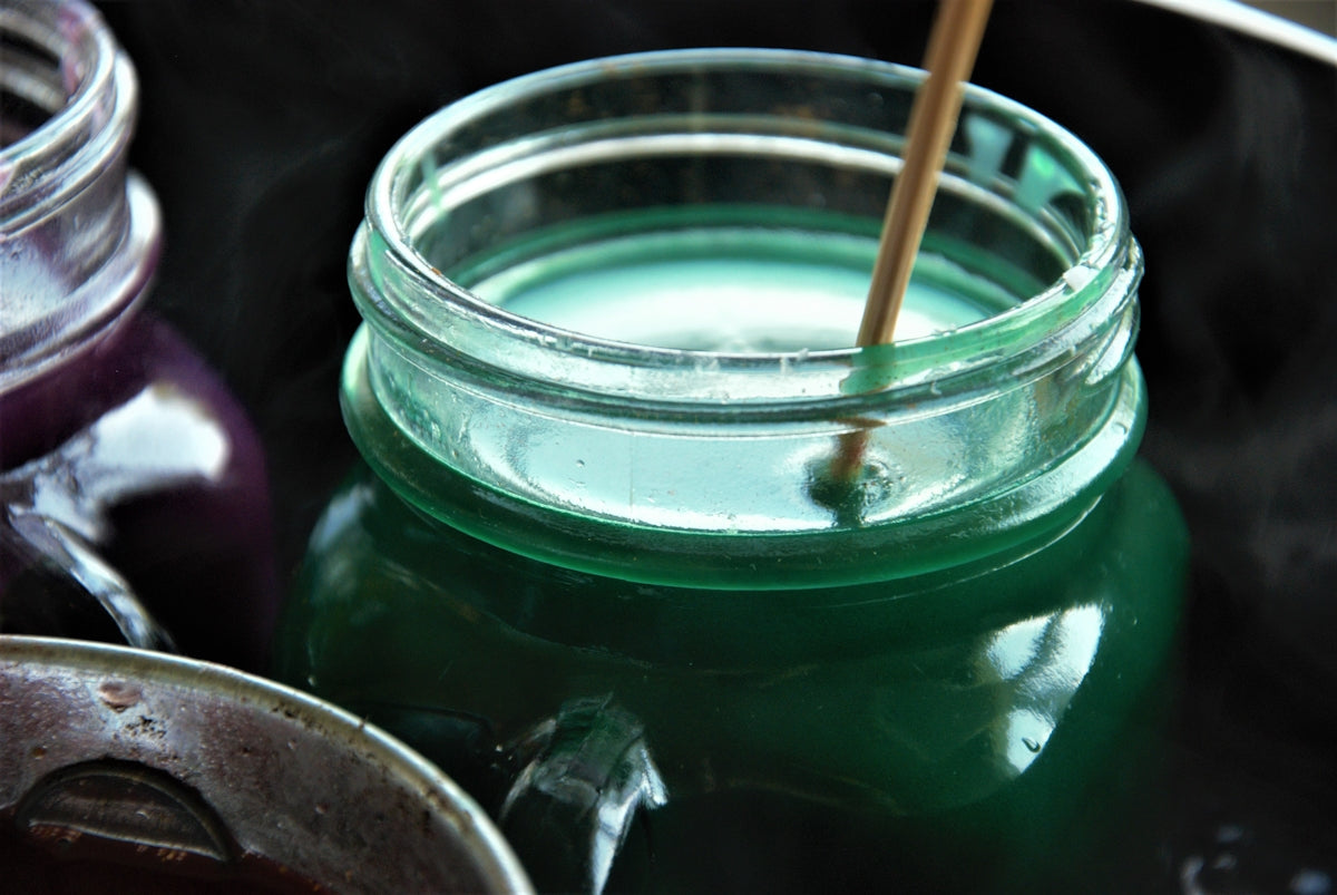 a jar of liquid with a wooden stick sticking out of it