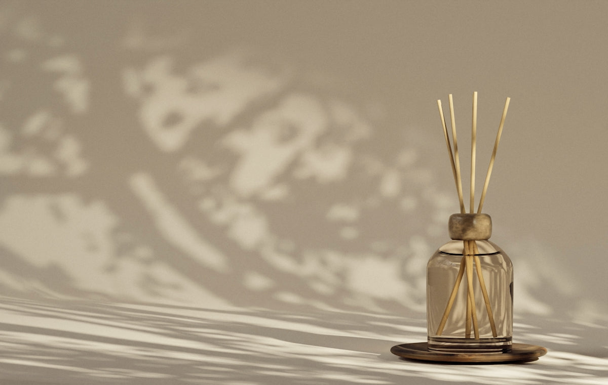 A reed diffuser casts shadows on a neutral background.