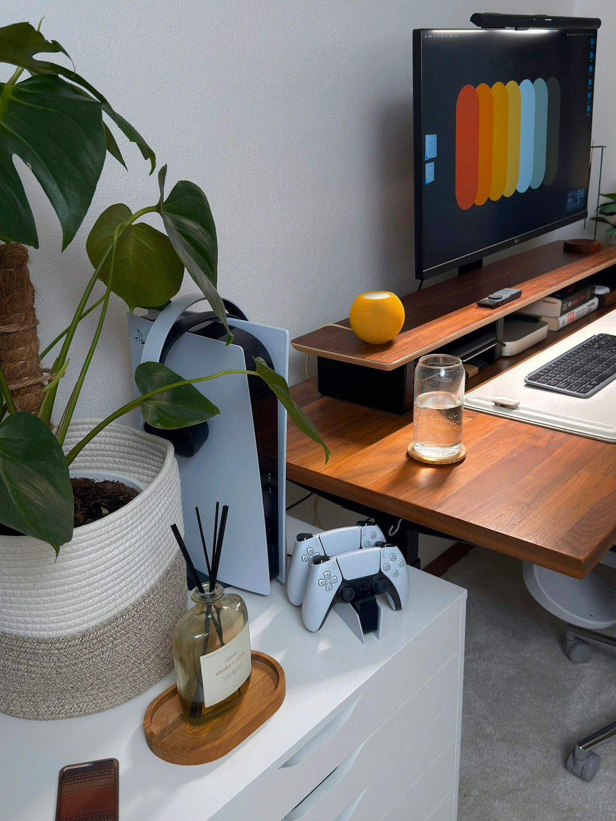 Desk with computer, gaming console, and plant.