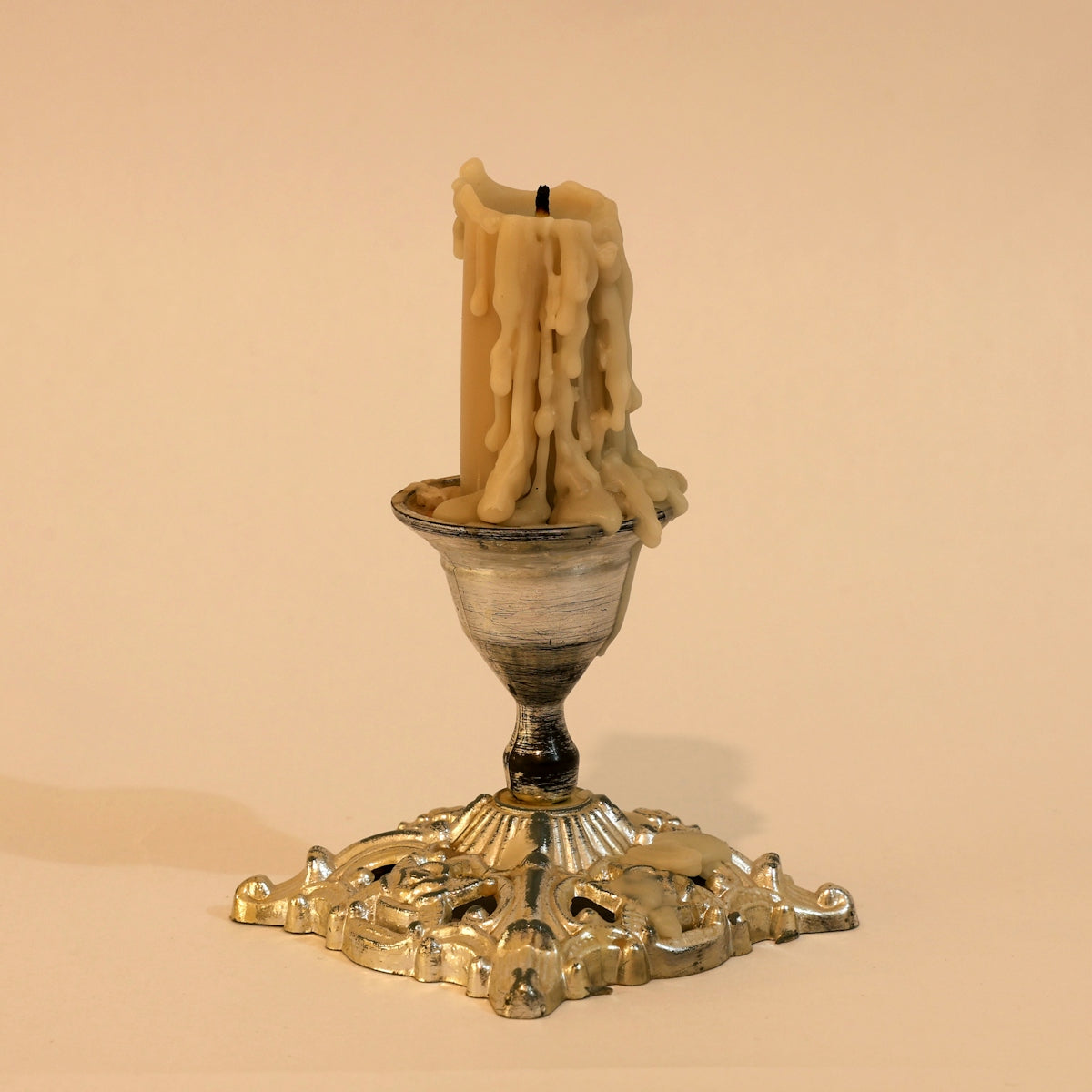 A melted candle in an ornate silver candlestick.